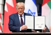 Trump Brokers Peace—Hezbollah Frozen Out Man in navy suit holding an open signed document at a ceremony