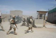 Drone Cleanup Turns Deadly In Iraq Soldiers in desert uniforms run past a checkpoint amid dust