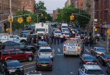 Police vehicles and officers block a city street during an active scene
