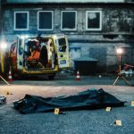 Police investigation at a crime scene with a covered body and evidence markers