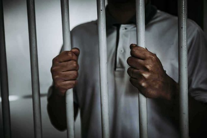 Person gripping prison bars with both hands