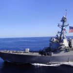 Trump Vows to Make Strait of Hormuz U.S. Territory Naval destroyer sailing on open sea with flag flying