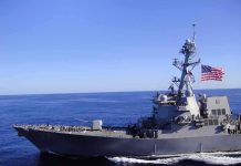 Naval destroyer sailing on open sea with flag flying