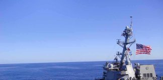 Trump Vows to Make Strait of Hormuz U.S. Territory Naval destroyer sailing on open sea with flag flying