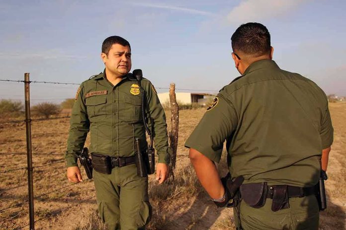 Two uniformed officers walking along a rural fence line