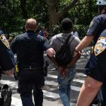 Armed Stalker Nabbed At Trump Golf Club Police escort a handcuffed man across a city street