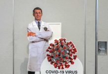 Cardboard cutout of doctor with COVID-19 virus info display