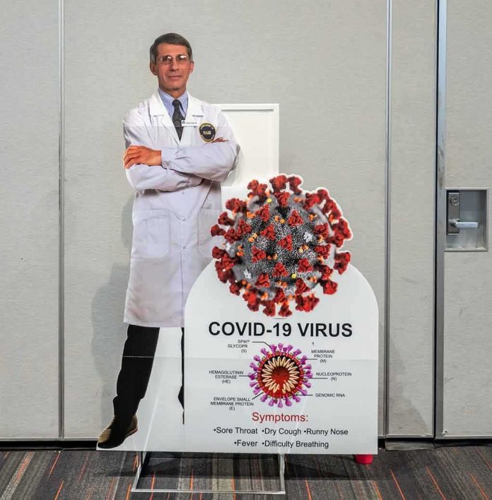 shutterstock_1949881045 Cardboard cutout of doctor with COVID-19 virus info display
