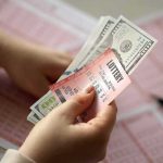 NYC Woman Trades $5K in Jewelry for ‘Winning’ Lottery Ticket Hands holding lottery tickets and U.S. dollar bills
