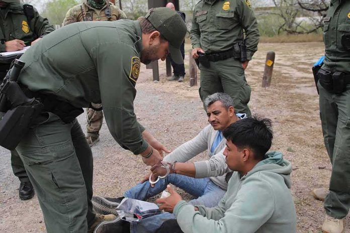 shutterstock_2270044315 law enforcement officer handcuffing two seated men outdoors