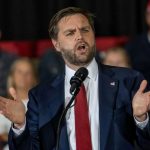 Vance Defends White House Media Ban Man in suit speaking at a podium