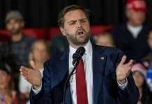 Vance Defends White House Media Ban Man in suit speaking at a podium