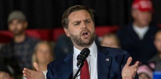 Vance Defends White House Media Ban Man in suit speaking at a podium