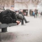 Person lying on a bench in an urban street