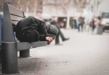Person lying on a bench in an urban street