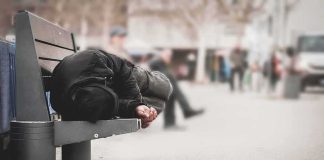 Person lying on a bench in an urban street