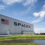 Starship Finally Does What It Never Could SpaceX hangar beside launch pad under blue sky