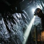 Trump Rekindles Coal Fight With Clinton miner with headlamp working in a dark tunnel
