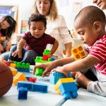 WHO Blasts Trump Vaccine Changes as Ignoring Science Karyn Polito with toddlers building blocks on a play mat