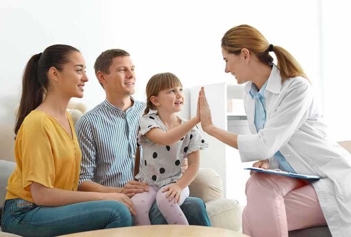 shutterstock_1280015026 Doctor high-fives a smiling child during family visit