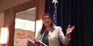 Woman speaking at a podium with hands raised