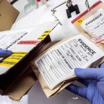 Gloved hands handling labeled evidence bags and boxes
