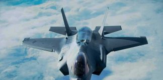 Stealth fighter jet flying above clouds