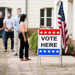 Voters wearing masks line up outside a polling place