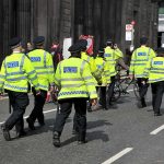 Police officers in high-visibility jackets walking on a city street