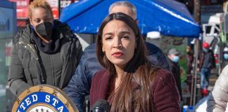 Woman speaking at outdoor press event with microphone and seal