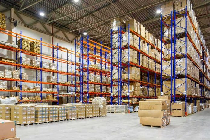 Warehouse aisles with tall blue and orange pallet racks filled with boxes