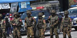Group of soldiers in camouflage uniforms standing in a street; Brenton Bersin and Shaquille Riddick present