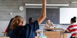Student raising hand in classroom during lesson