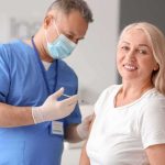 Doctors Can’t Be Punished for Rejecting Government COVID Claims Smiling woman receiving a vaccination from a healthcare worker