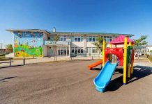 22 Children at Center of Paris Nursery Horror Playground with colorful slide in front of a school building