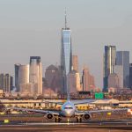 Airplane taxiing on runway with city skyline in background