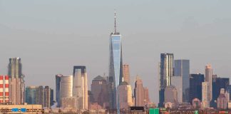 Airplane taxiing on runway with city skyline in background