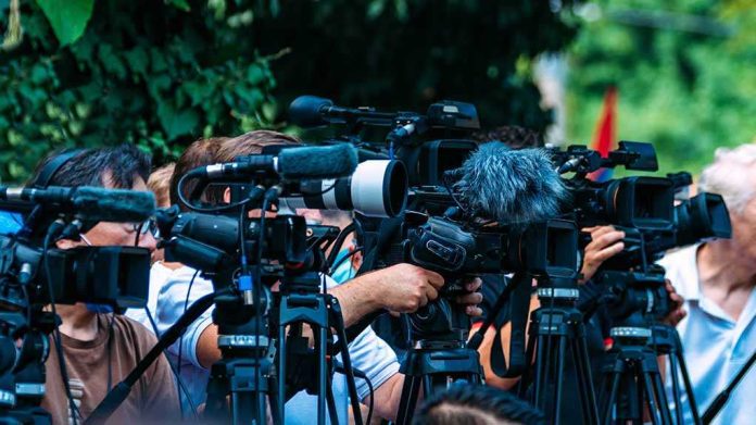 shutterstock_2210577723-5 TV news cameras crowding together at an outdoor event