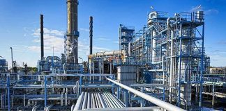 Industrial refinery with pipelines and distillation towers under blue sky