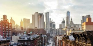 City street leading to a skyline of modern and historic skyscrapers at sunset