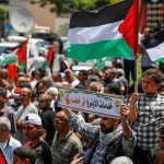 Soaring Fuel Prices IGNITE Protests Worldwide Crowd of protesters holding Palestinian flags in a street demonstration