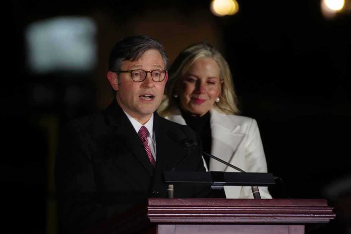 Man speaking at a podium with a woman standing behind him