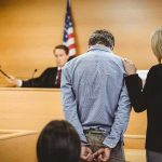 Former U.S. Marine Freed After More Than 4 Years in Russia Defendant in handcuffs stands before a judge in a courtroom