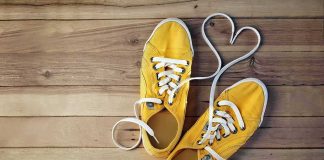 Yellow canvas sneakers with laces forming a heart on wooden floor