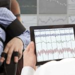 ICE’s ‘Bee Sting’ Shock Gloves Explained Technician reviews polygraph readings on a tablet beside a seated subject