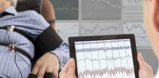 Technician reviews polygraph readings on a tablet beside a seated subject