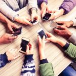 Hands around a table holding smartphones