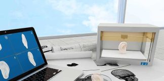 3D printer and laptop creating a model ear on a lab desk