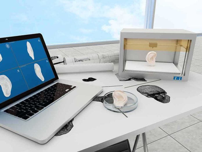 shutterstock_417469165 3D printer and laptop creating a model ear on a lab desk