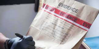 Gloved hands labeling a sealed evidence bag